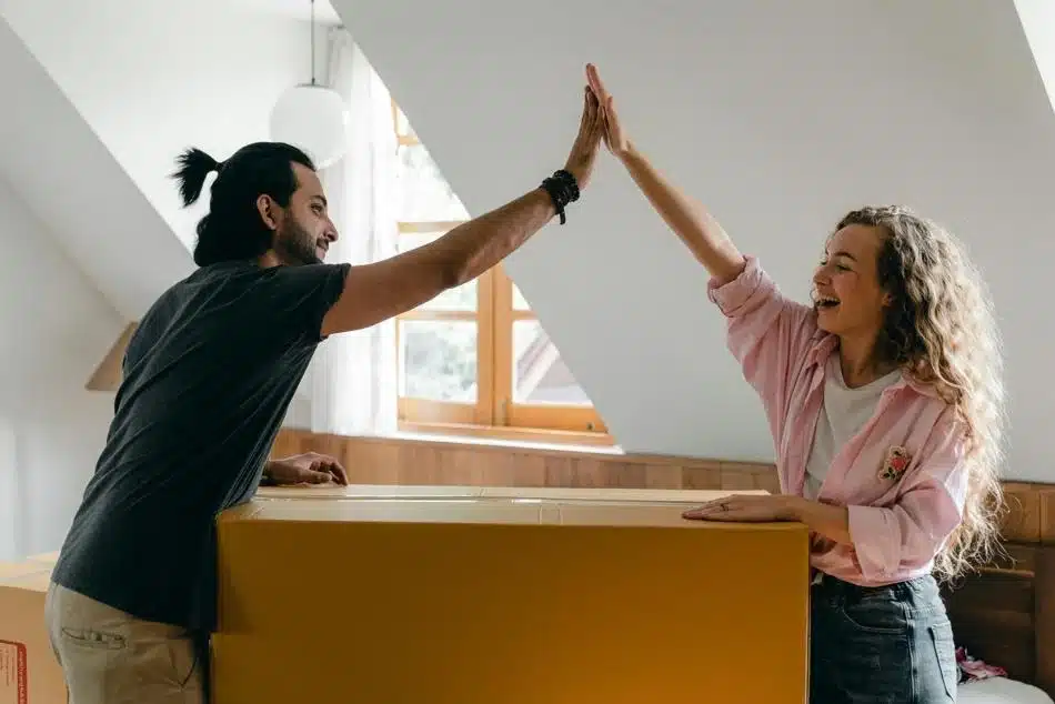 2 people high fiving after packing up a large box while moving